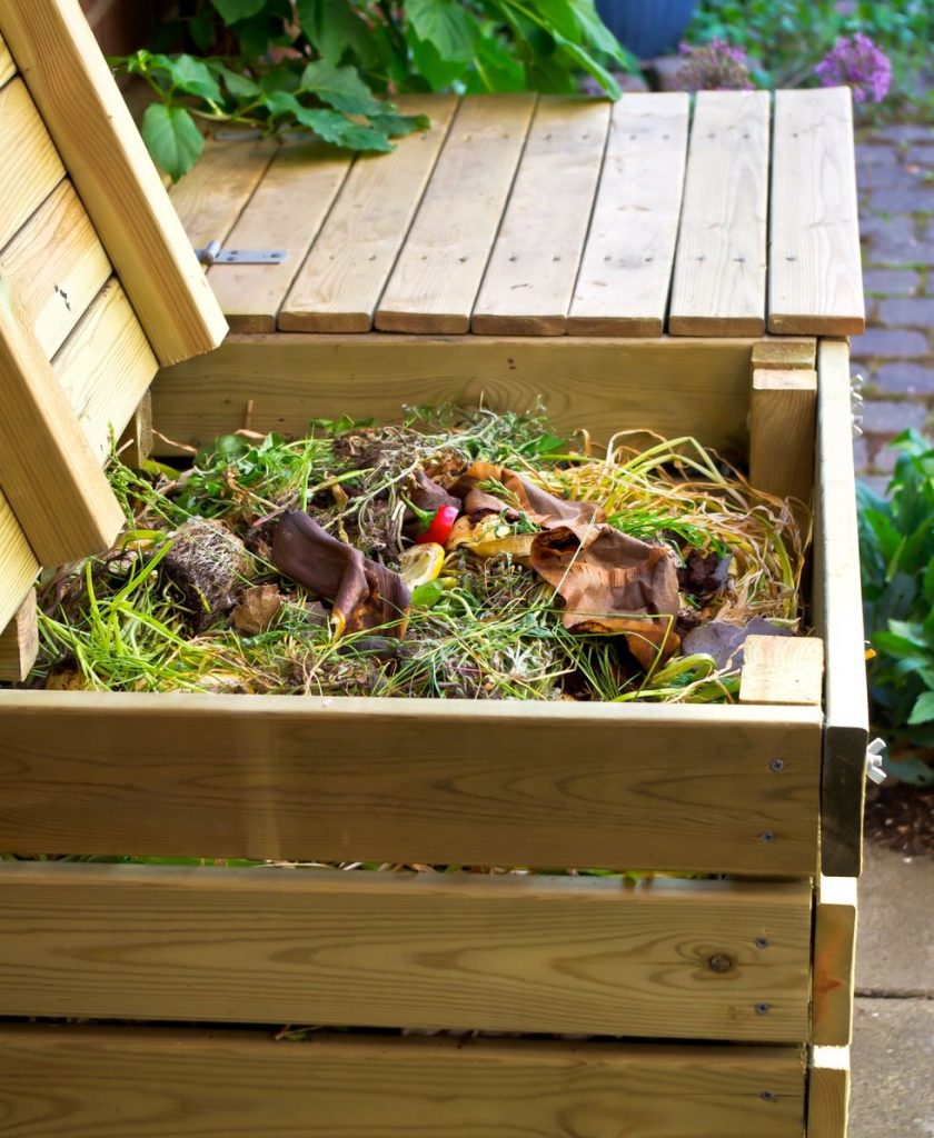 Homemade compost in a wooden bin for improving indoor vegetable garden soil.
