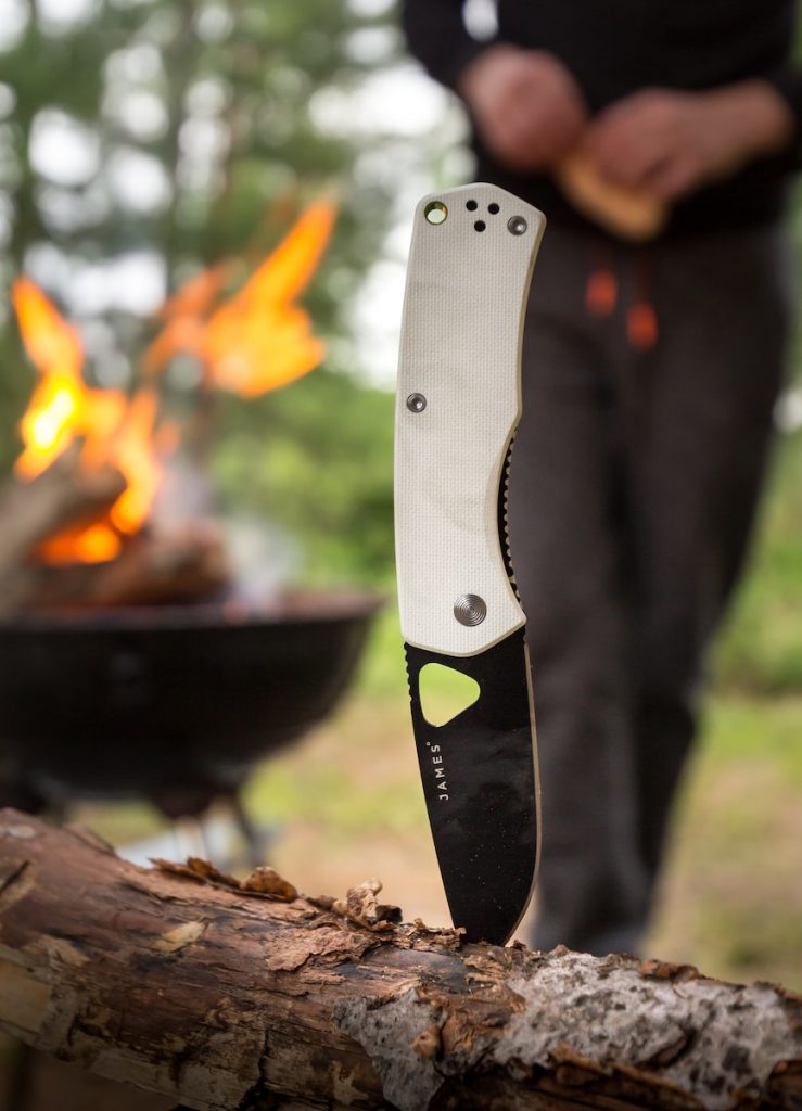 white and black James pocketknife sticking on branch