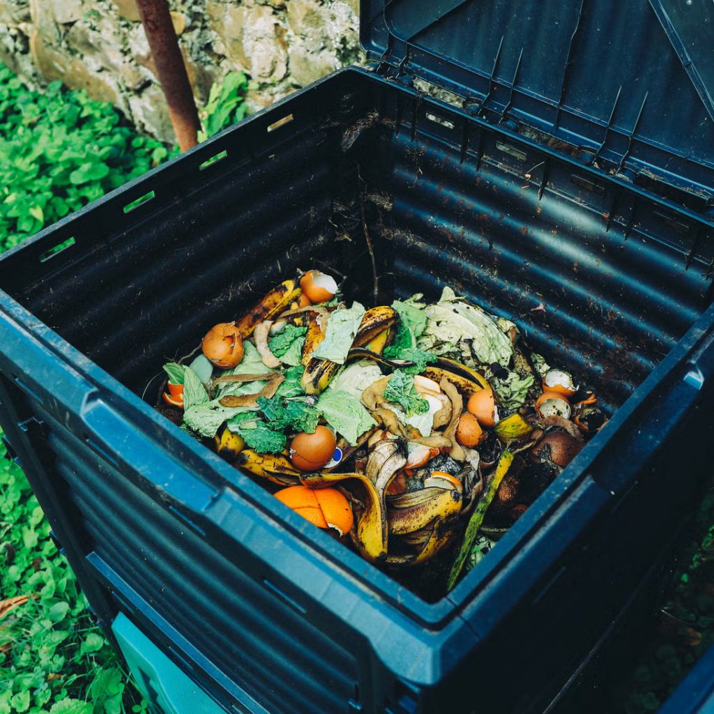 different home composting systems including a bin and tumbler in a small garden.