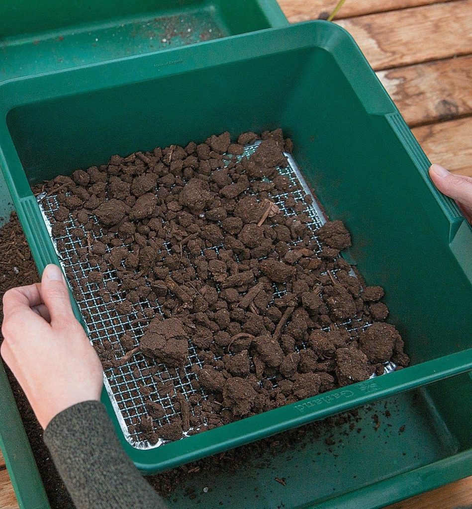 Sifting old compost to reuse potting soil indoors